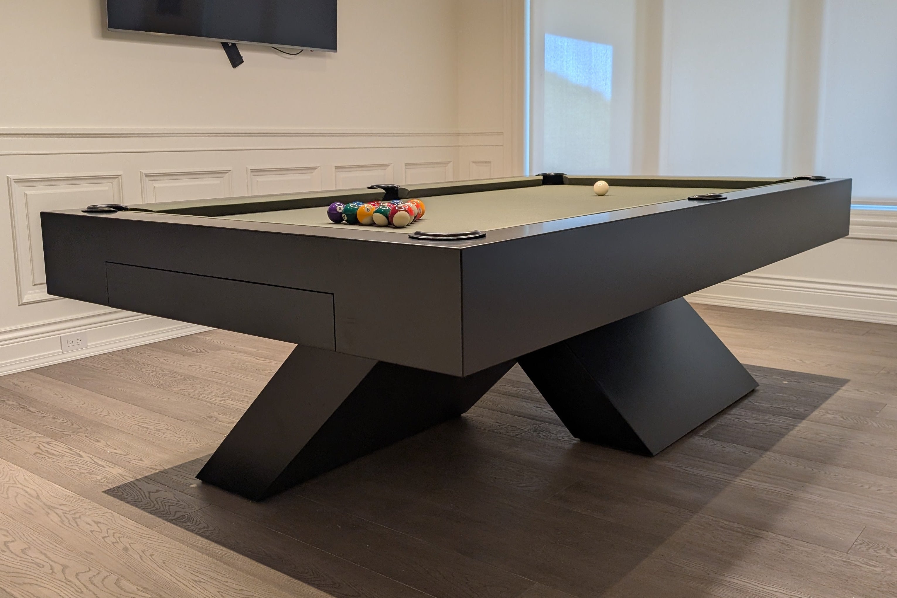 Modern pool table in a room with a television mounted on the wall.1621243260e1af0c20-0