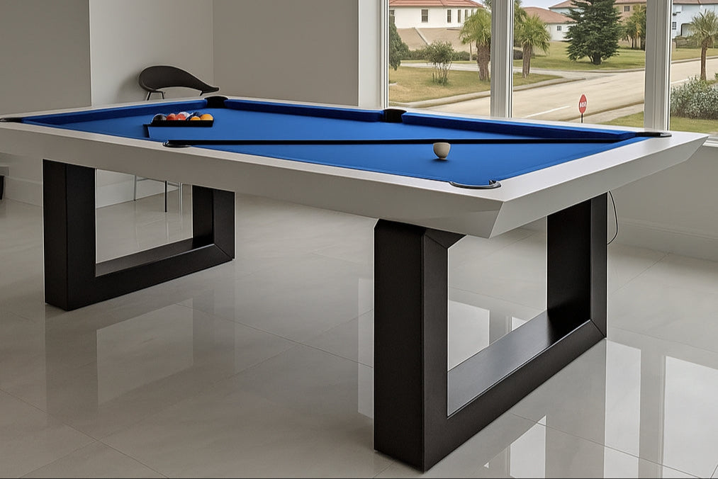 A modern billiard table with a blue felt top, black and silver legs, and accessories including cues and chalk.