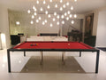 Modern pool table with red felt surface in a stylish room with chandelier and sofa.
