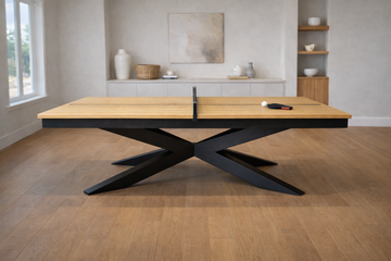 Wooden ping pong table with black metal base in a room with light wood flooring and white walls.