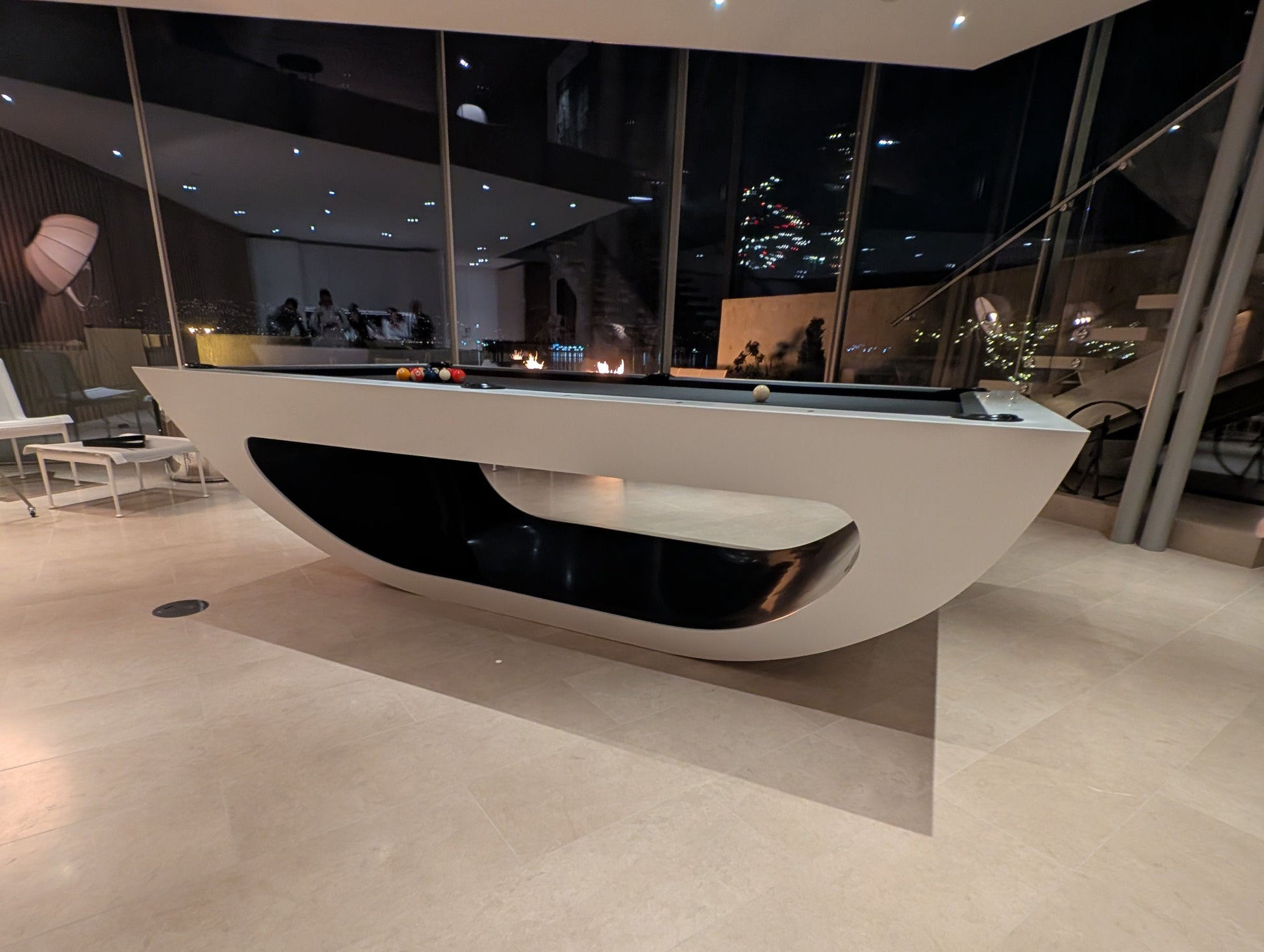 Modern indoor pool with reflective floor and glass walls at night