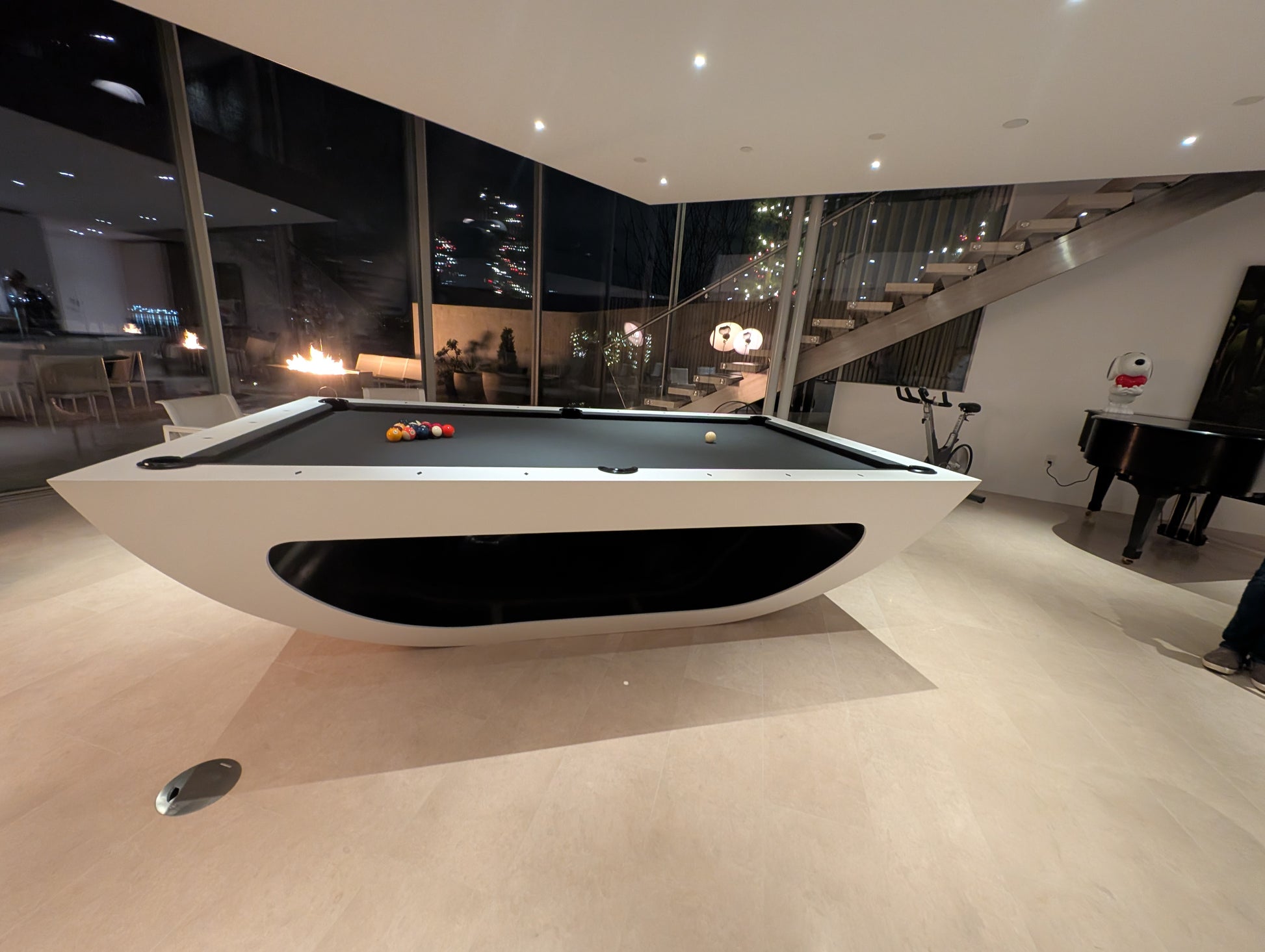 Modern pool table in a stylish room with large windows at night.