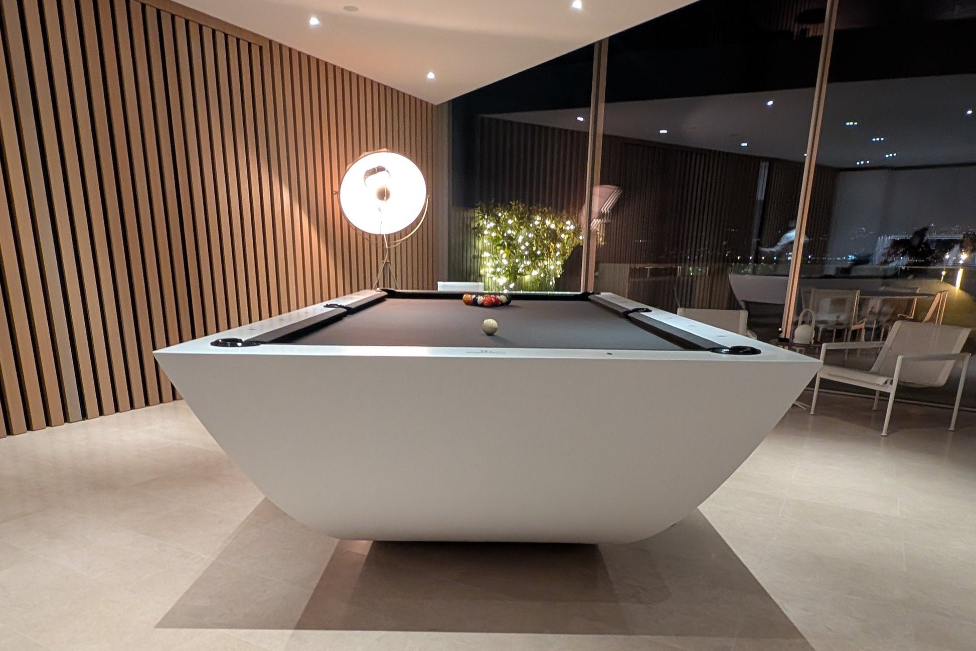 Modern pool table in a stylish room with wooden walls and a light floor.