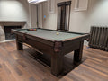 Pool table in a room with wooden flooring and a fireplace.