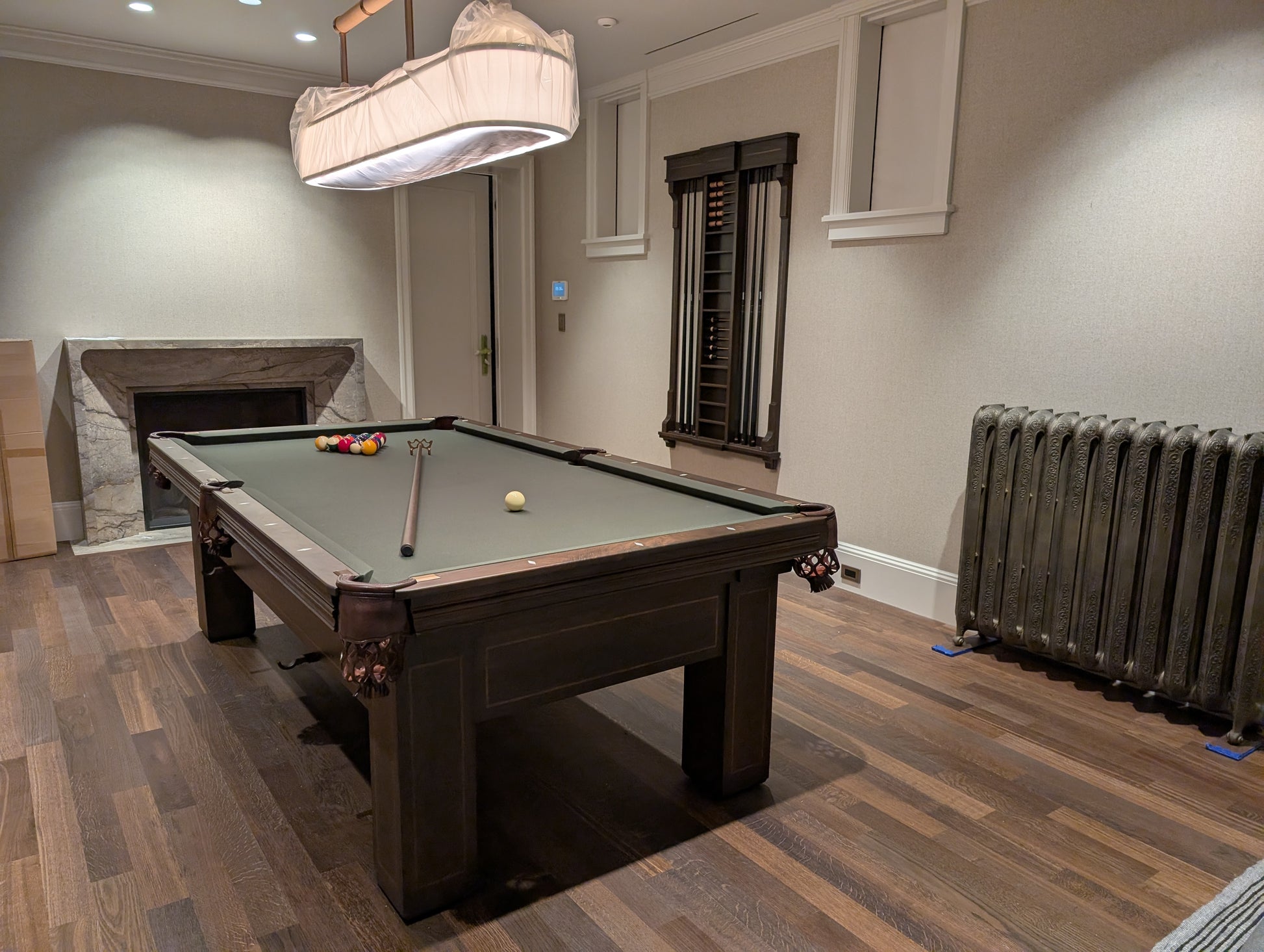 Pool table in a room with wooden flooring and a radiator.