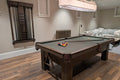 Pool table in a room with wooden flooring and a chandelier.