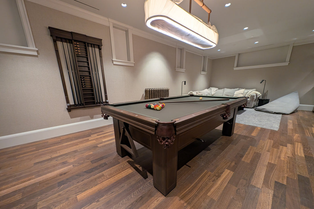 Pool table in a room with wooden flooring and a chandelier.