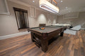 Pool table in a room with wooden flooring and a couch in the background