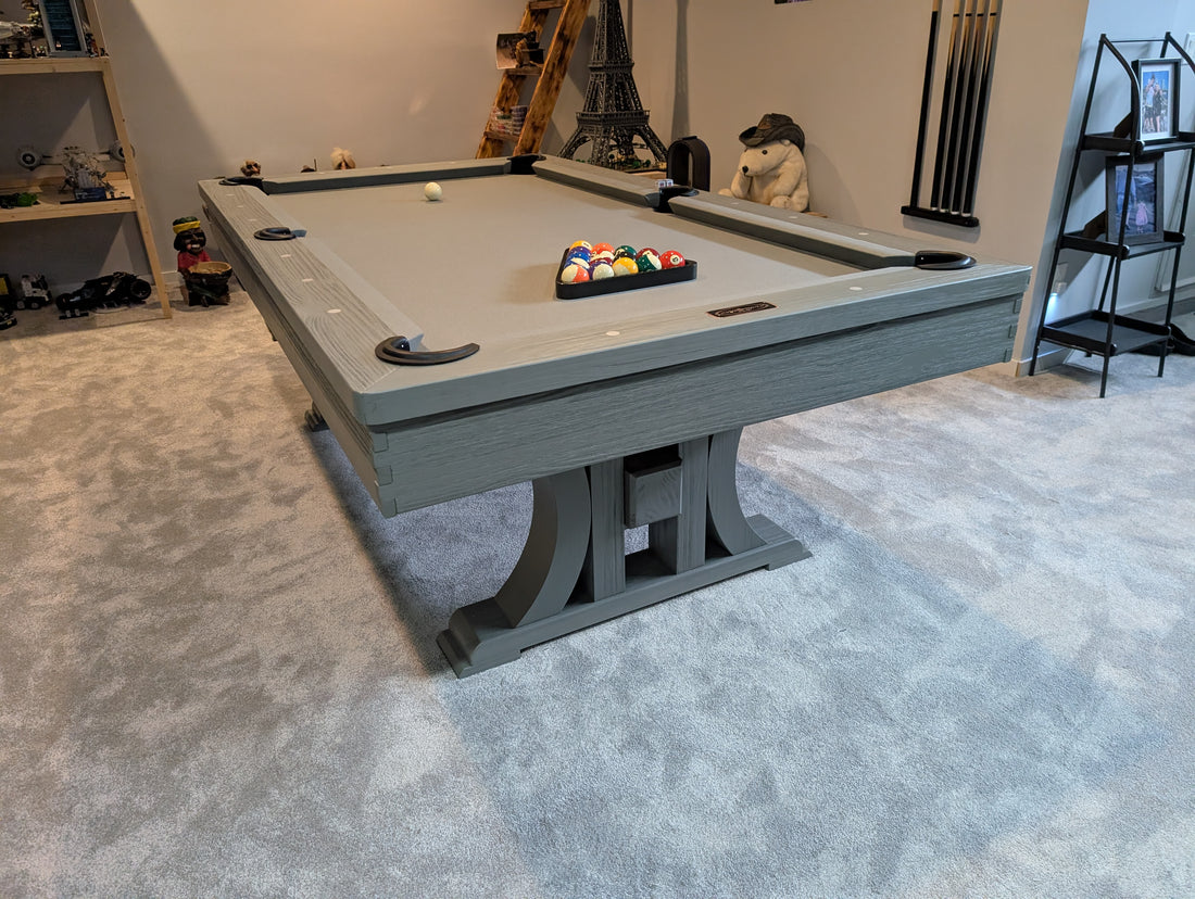 Pool table with billiard balls in a room with shelves and decor.