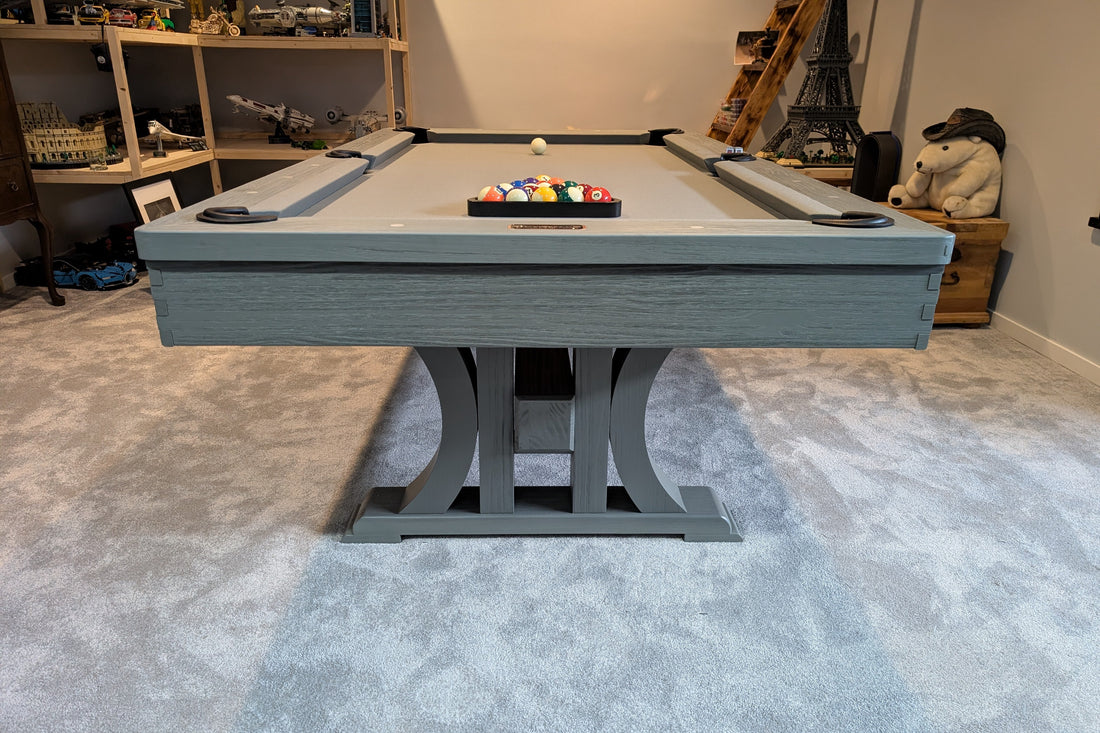 Pool table with billiard balls in a room with shelves and decor.
