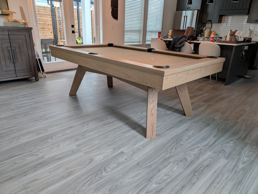 Wooden pool table in a room with large windows and modern decor.