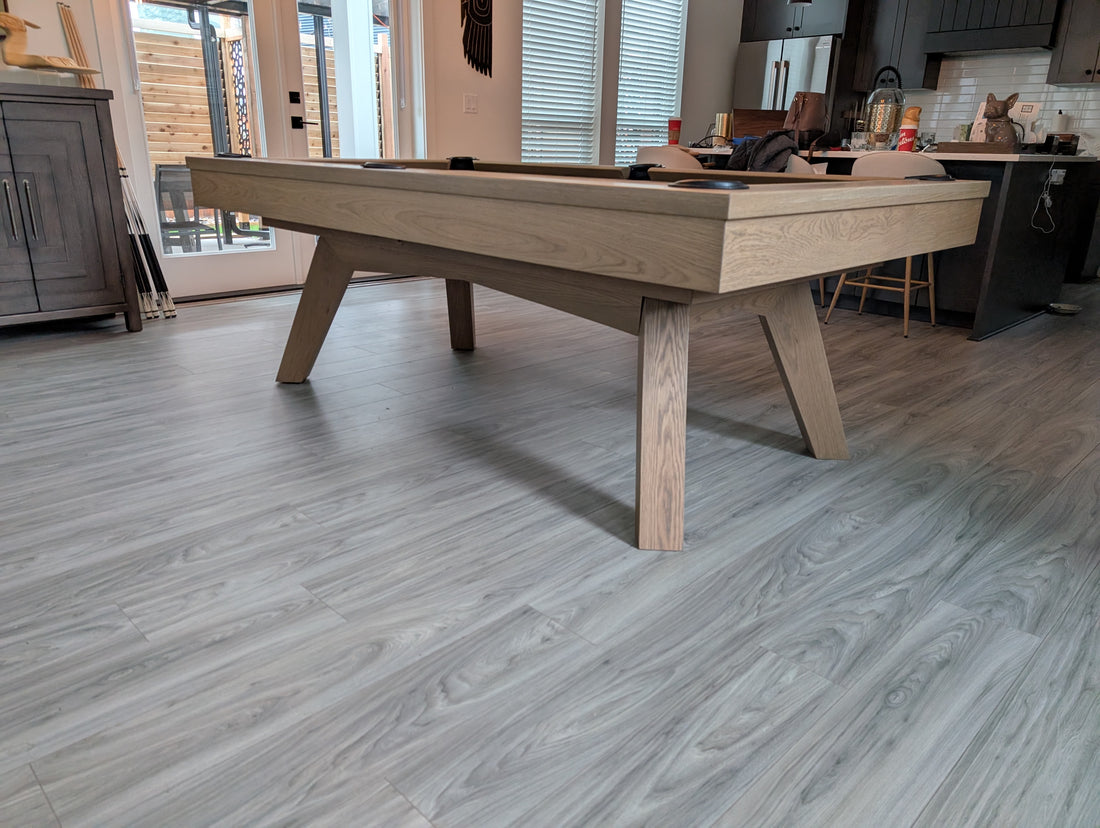 Wooden pool table in a room with large windows and modern decor.