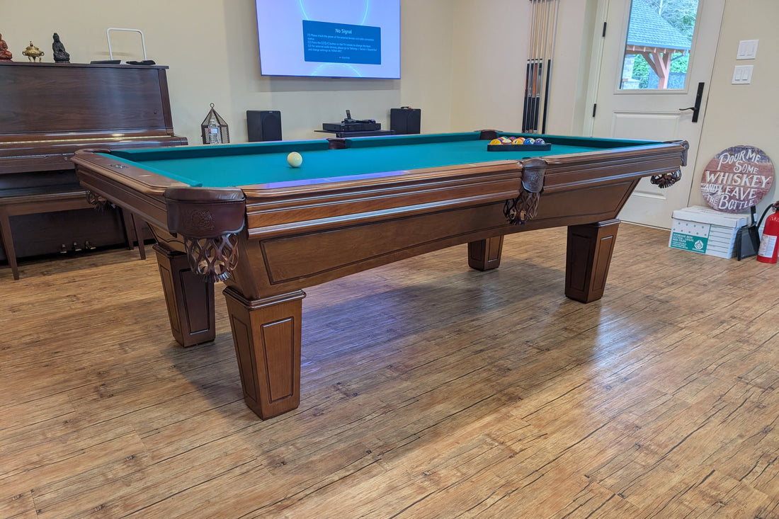 Pool table in a room with wooden flooring and a television in the background.