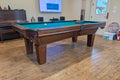 Pool table in a room with wooden flooring and a television in the background.