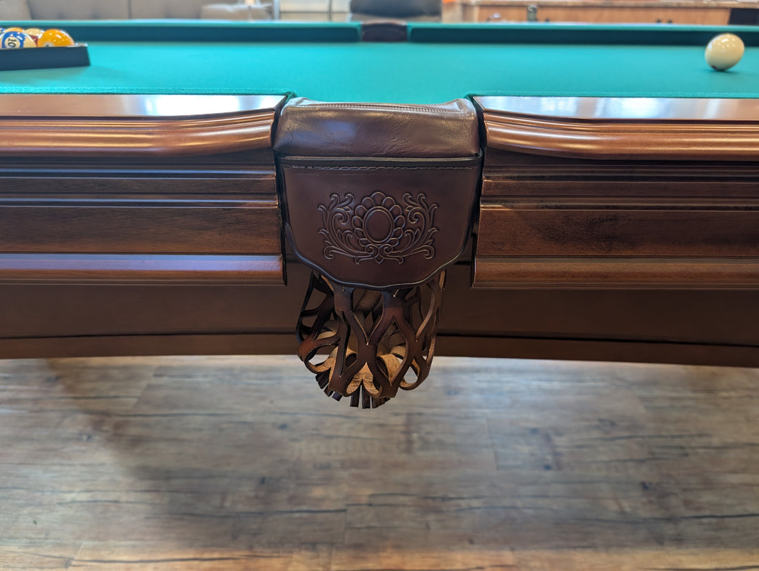 Pool table in a room with wooden flooring and a television in the background.