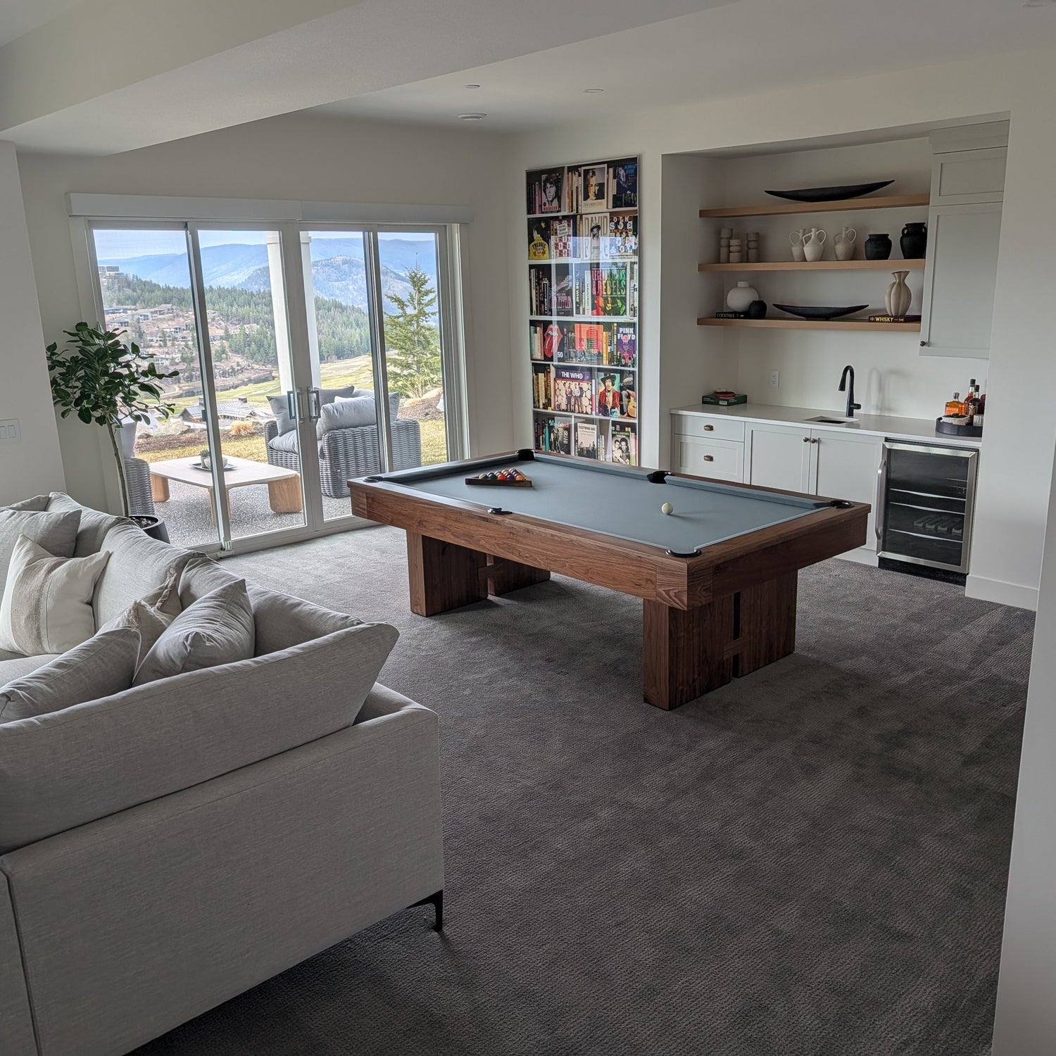 Living room with a pool table, gray sofa, and kitchen area.